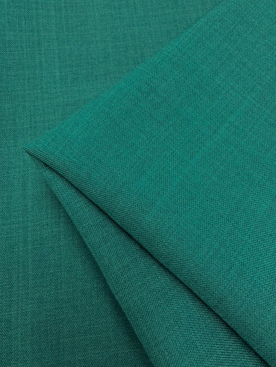 Folded Twill Suiting - Ivy (150cm) by Super Cheap Fabrics in teal-green with a subtle diagonal weave, layered on matching fabric to showcase its versatile style.