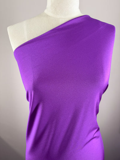 A mannequin displays Super Cheap Fabrics’ Nylon Lycra - Magenta - 154cm, a bright magenta one-shoulder swimwear fabric with four-way stretch and medium weight, smoothly fitted with the right shoulder exposed against a plain light background.