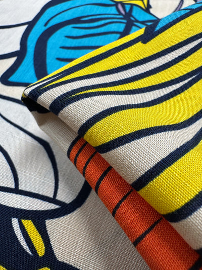 A close-up of Super Cheap Fabrics’ Bamboo Rayon - Big Boldy (150cm) shows its lightweight, textured weave and vibrant pattern with yellow, blue, black, white, and orange lines and shapes.
