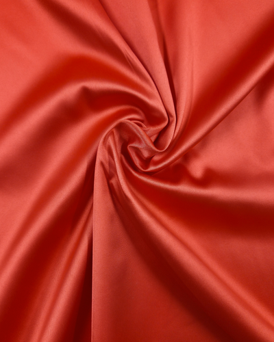 Close-up of Super Cheap Fabrics' Satin Deluxe in Grenadine, 150cm, twisted into a spiral pattern to showcase its smooth, glossy texture and shiny finish.