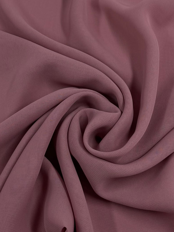 A close-up of Super Cheap Fabrics' Hi-Multi Chiffon in Blush (148cm), showing its soft, sheer mauve fabric with a smooth texture, elegantly gathered into gentle folds and swirling patterns at the center.