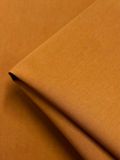 Close-up of Super Cheap Fabrics’ Plain Cotton - Marmalade - 150cm, showing smooth, evenly colored 100% cotton fabric with neat edges and a soft matte finish. The lightweight material looks refined and crisp.