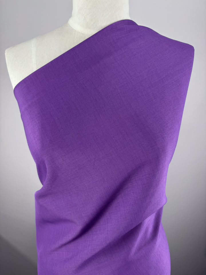 A white mannequin displays Super Cheap Fabrics' Twill Suiting - Amethyst Orchid - 150cm, draped across one shoulder and the torso. The polyester fabric features a subtle diagonal twill weave, shown against a plain neutral background.