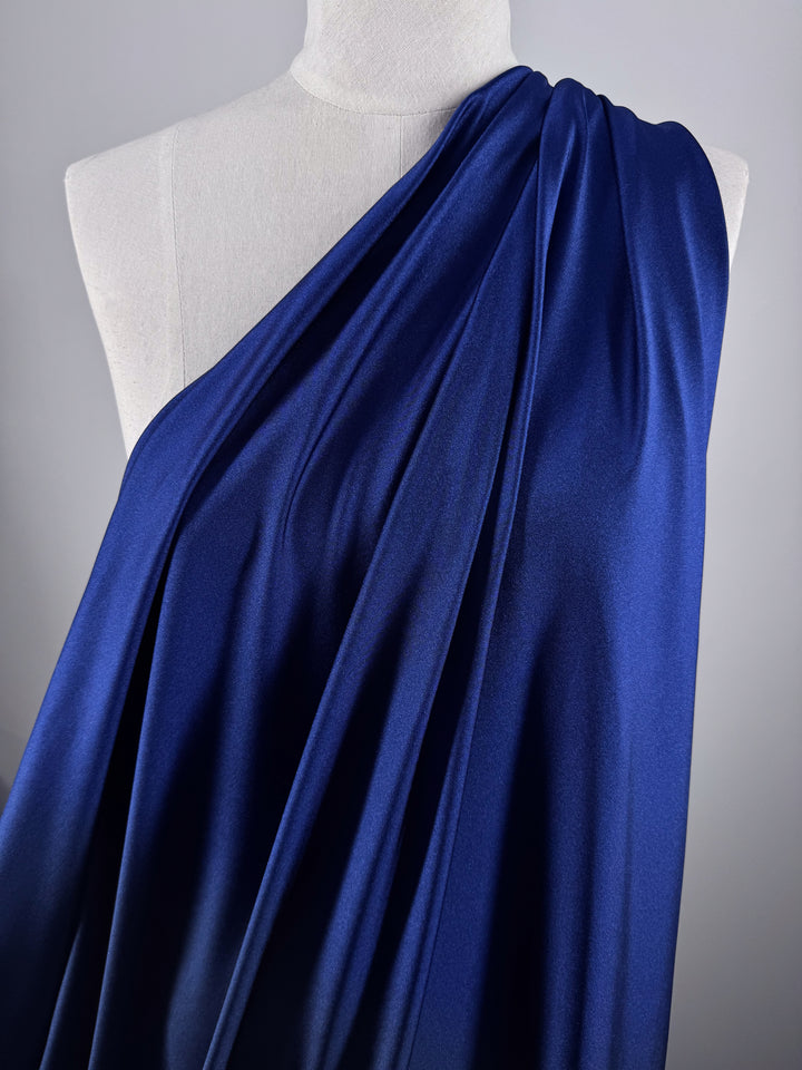 A mannequin displays Super Cheap Fabrics’ Nylon Lycra - Midnight Sail (154cm), draped over one shoulder to highlight its deep blue shade, glossy finish, four-way stretch, and elegant folds.