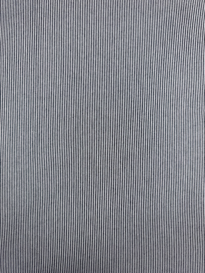 Close-up of Super Cheap Fabrics' Designer Cotton - Pintrack - 150cm, a medium weight cotton with thin, evenly spaced black and white vertical pinstripes creating a fine linear pattern across the fabric’s surface.