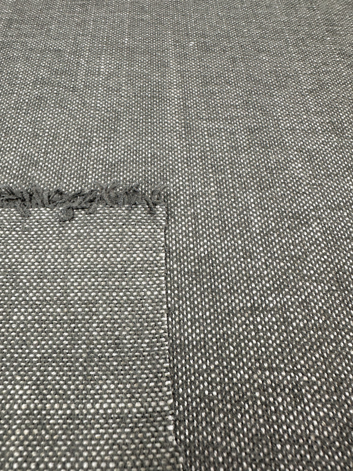 Close-up of Upholstery Basket Weave - Dresden Warm Silver by Super Cheap Fabrics, featuring a medium weight gray textured fabric with a fringe on the left and a rectangular piece overlying the background, showcasing its intricate structured basket weave pattern. Fabric width: 145cm.