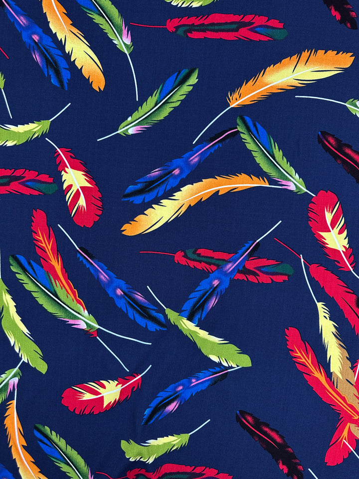 Bamboo Rayon - Feather Blue by Super Cheap Fabrics features a vibrant, beginner-friendly pattern of colorful feathers on dark blue. Lightweight and 150cm wide, it’s perfect for sewing projects that need a lively touch.