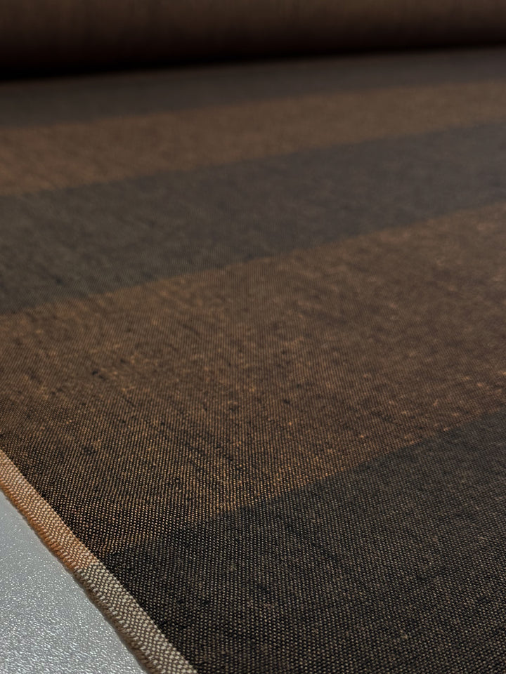 A close-up of Linen Viscose - Rustline Canvas (145cm) by Super Cheap Fabrics shows its brown and black stripes, textured weave, and rolled edge—perfect for upholstery or clothing projects.