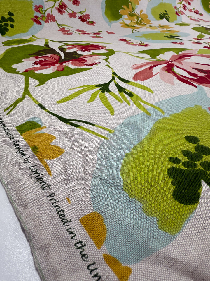 Close-up of Pure Linen - Garden Reverie - 150cm by Super Cheap Fabrics, featuring a vibrant green, pink, and yellow floral pattern. Edge displays designer details and UK printing. This is a deadstock fabric from the Garden Reverie collection.