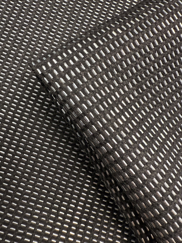 A close-up of Super Cheap Fabrics' Linen Blend - Silver Dash (135cm) highlights its grid pattern of raised, shiny rectangles, with one luxurious piece draped diagonally over another—ideal for sophisticated upholstery projects.