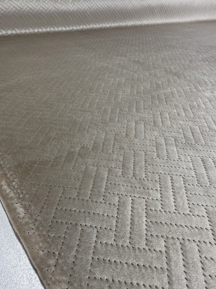 A close-up of Embossed Velvet - Oatmeal by Super Cheap Fabrics: a beige, extra heavy weight fabric with a subtle geometric basketweave pattern—luxuriously soft and perfect for upholstering sofas or armchairs.