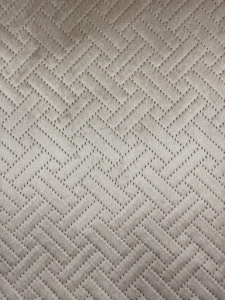 Close-up of Super Cheap Fabrics’ Embossed Velvet - Oatmeal (150cm), an extra heavy weight, beige fabric with a repeating herringbone pattern and small, evenly spaced perforations—ideal for upholstering sofas and armchairs.