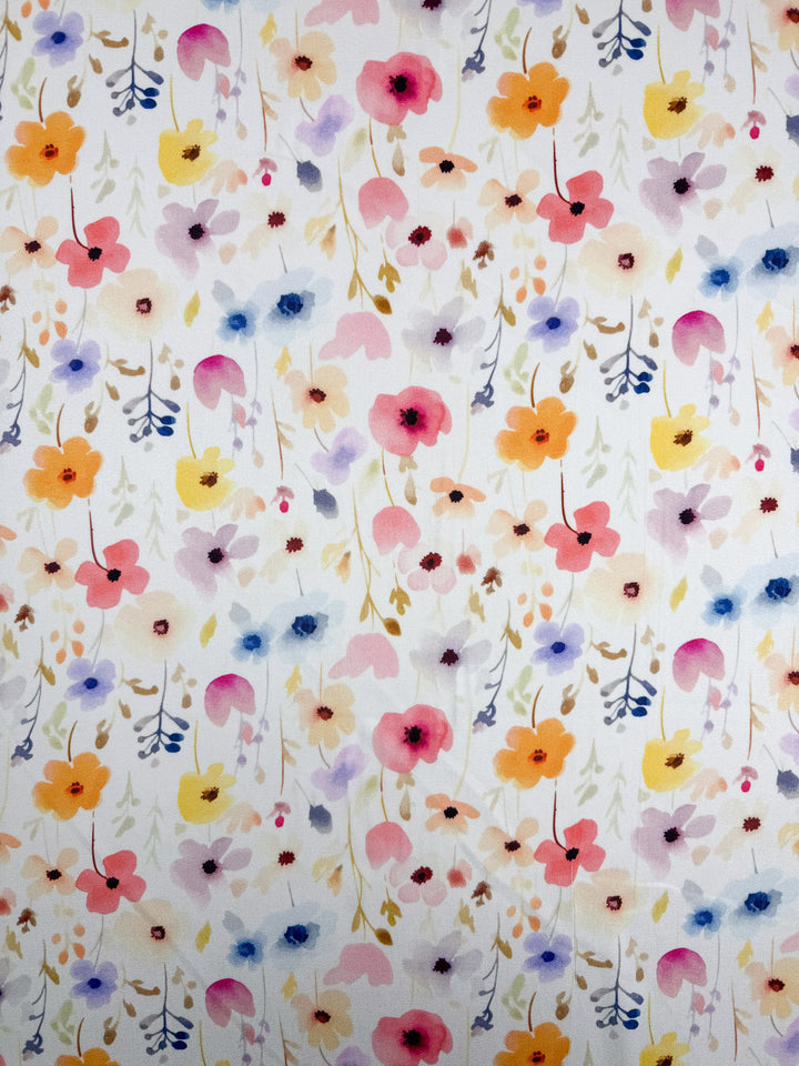Super Cheap Fabrics' Mercerised Rayon - Meadowdrop (150cm) features a seamless watercolor flower pattern in pink, orange, yellow, purple, and blue with green and brown leaves on white—ideal for lightweight or breathable fabric projects.