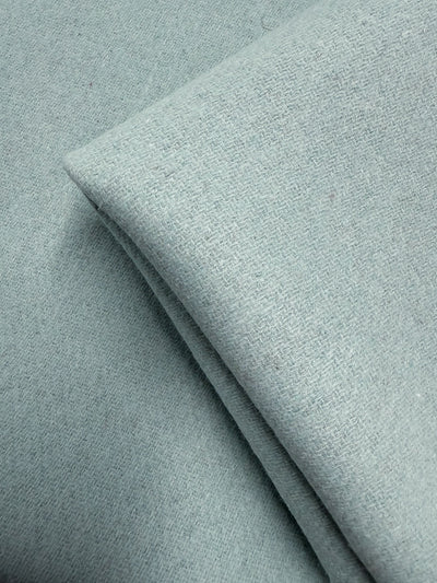 A close-up of Wool Cashmere - Blue Glass - 150cm from Super Cheap Fabrics shows its light blue hue, subtle textured weave, and luxurious softness.