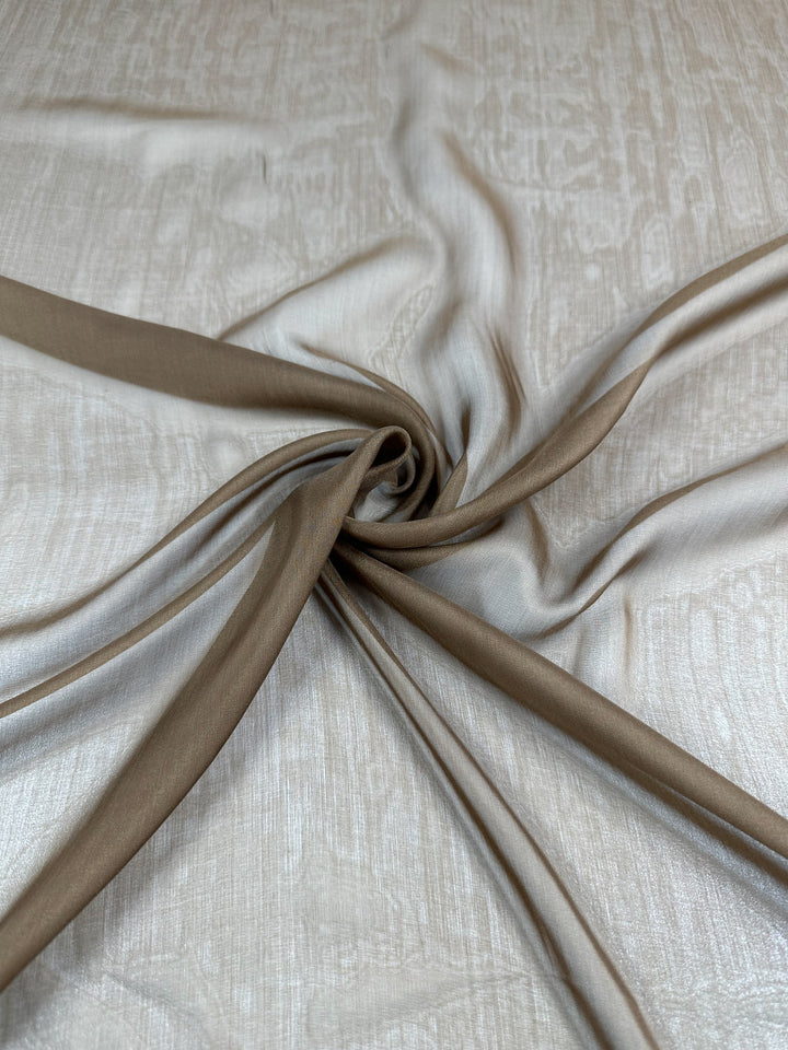 Super Cheap Fabrics’ Silk Chiffon - Coca Mocha - 112cm is an extra lightweight, sheer silk fabric that’s artfully twisted at the center, creating gentle folds and flowing lines across a soft, textured surface.