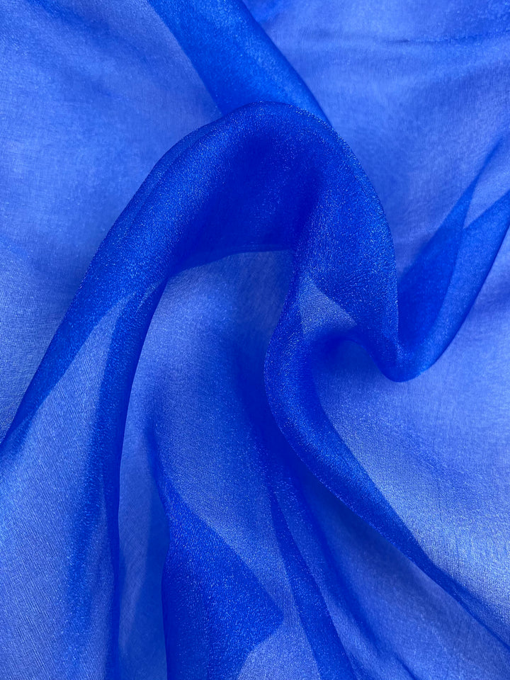 A close-up of Super Cheap Fabrics’ Organza - Royal - 150cm in blue, highlighting its smooth, sheer, and lightweight texture with delicate folds and translucence.
