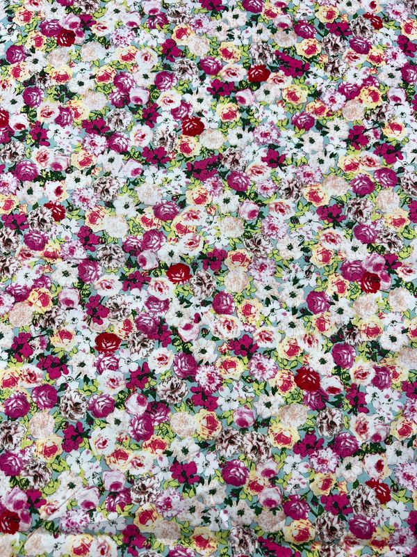 Introducing the Roseness - 120cm from Super Cheap Fabrics, a printed cotton featuring a vibrant floral pattern adorned with an array of pink, red, white, and yellow roses. The predominantly light background enhances these colorful blossoms while highlighting the natural cotton fibers, perfect for various creative projects.